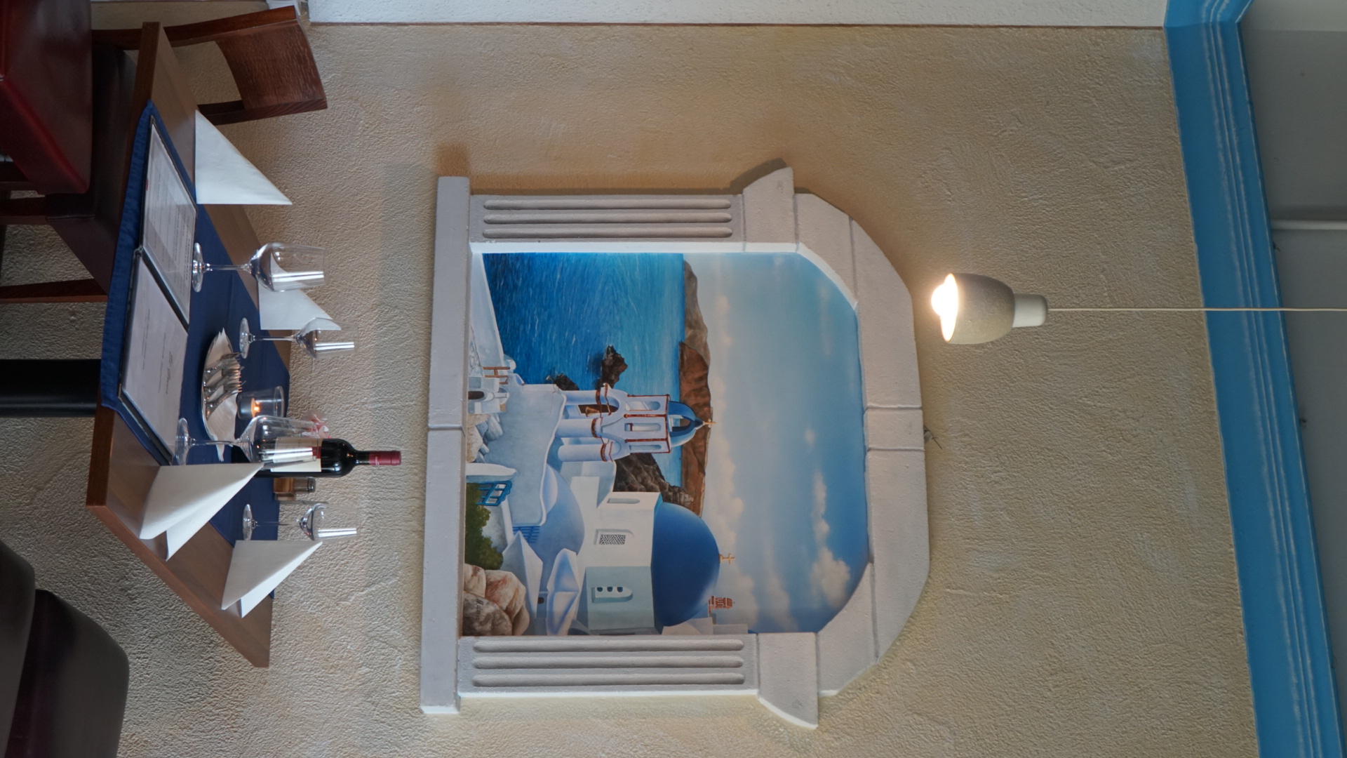 Gedeckter Tisch im El Greco vor einem gemalten Fenster mit Santorini-Motiv